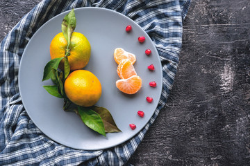 Fresh tangerines on dark slate. Pomegranate seed decoration.