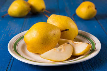 Fresh ripe organic yello pears on blue rustic wooden table, natural background, diet food.