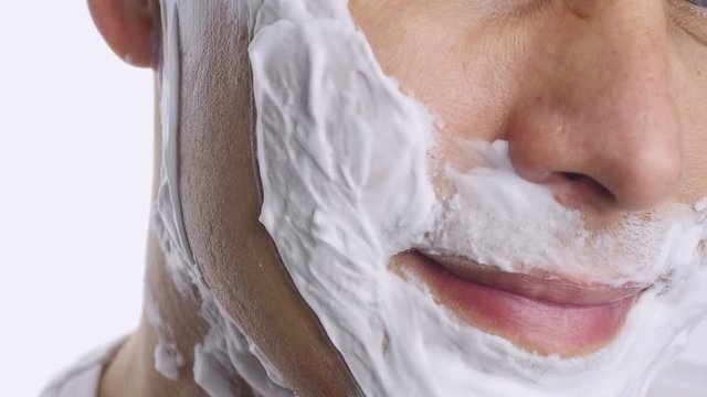 Man shaving with foam and manual razer. 
