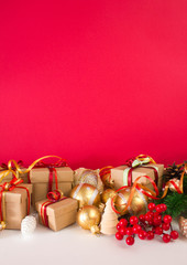 Christmas or New Year background: fur-tree, branches, gifts, colored glass balls, decoration and cones on a red background