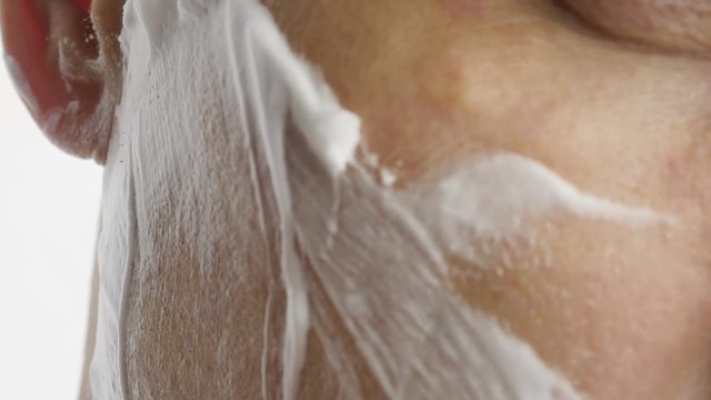 Man shaving with foam and manual razer. 
