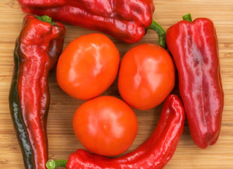 Red fresh pepper and tomato fruits on wooden Board
