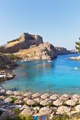 Fototapeta na wymiar The sandy beach of St. Pauls Bay with clear blue water - a favorite place of rest in the town of Lindos, Rhodes