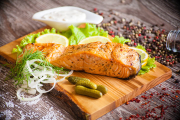 grilled salmon on a wooden board with lemon and lettuce, served