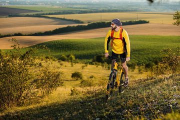 Fototapeta na wymiar Young cyclist on a rural road through green spring meadow