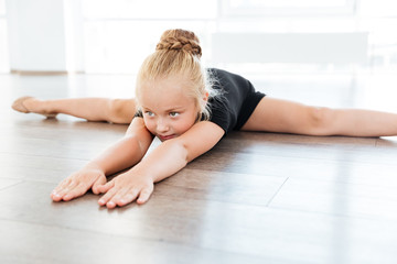 Little ballerina stretching and doing twine in dance studio