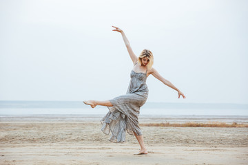 Obraz premium Woman dancer in long dress dancing barefoot on the beach