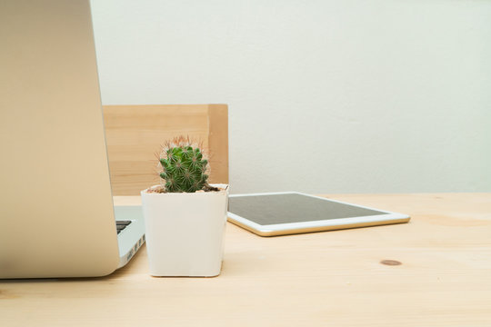 Office table with cactus flower on pot and laptop, tablet.