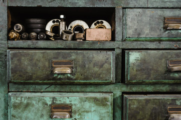 Old green workshop drawers with machine gear (I)