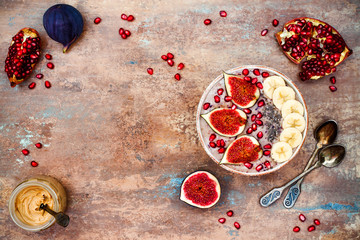 Healthy fall and winter breakfast set. Acai superfoods smoothies bowl with chia seeds, pomegranate, sliced banana, fresh figs and hazelnut butter. Overhead, top view. Copy space
