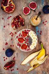 Healthy fall and winter breakfast set. Acai superfoods smoothies bowl with chia seeds, pomegranate, sliced banana, fresh figs and hazelnut butter. Overhead, top view.
