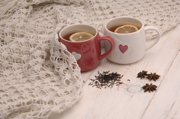 two cups of tea with lemon and scarf on wooden boards