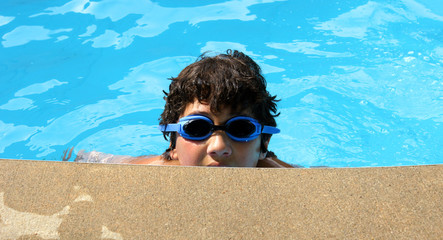 Boy wearing blue goggles in the swimming pool