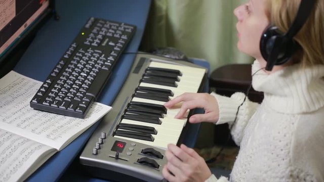 woman writes music on the computer. digital piano midi keyboard