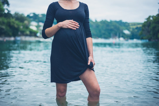 Young pregnant woman standing in a lake