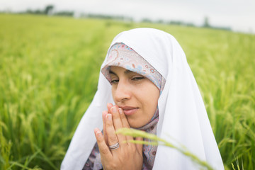 Beautiful happy Muslim woman in green field