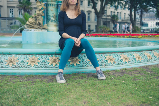 Young woman sitting by fountain