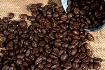 Arabica coffee beans in small tank on sack backgrounds