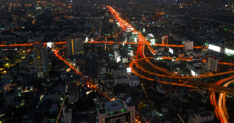 Futuristic night cityscape aerial view panorama with illuminated skyscrapers and city traffic across street. Bangkok, Thailand
