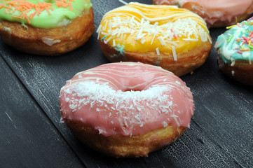 Fresh tasty donuts in soft colorful glaze on a wooden background