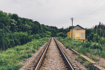 Fototapeta na wymiar railway tracks in the woods and a house with an edge