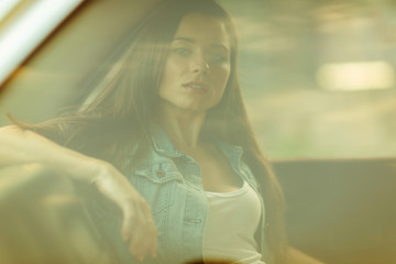 Brunette sitting in car behind closed window, tinted photo