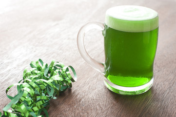 Single glass of green beer and shiny ribbons