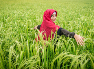 Naklejka na ściany i meble Beautiful happy Muslim woman in green field