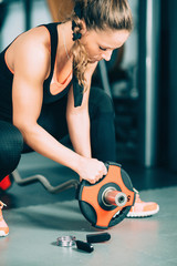 Obraz na płótnie Canvas Female athlete setting up barbell weights
