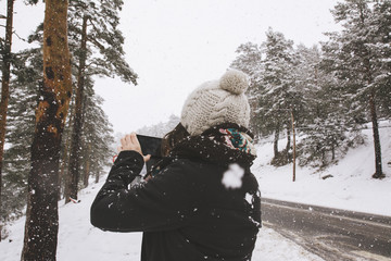 Unknown woman taking shot on smartphone?at snowfall.
