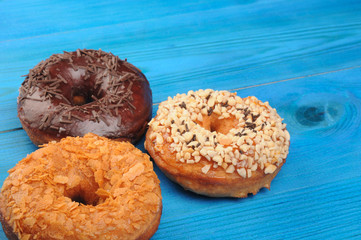 Fresh tasty donuts in soft colorful glaze on a blue wooden background