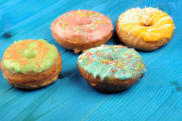 Fresh tasty donuts in soft colorful glaze on a blue wooden background
