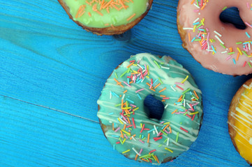 Fresh tasty donuts in soft colorful glaze on a blue wooden background