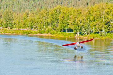 Alaskan float plane takes off from a river.
