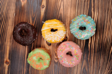 Fresh tasty donuts in soft colorful glaze on a grunge dark aged wooden background