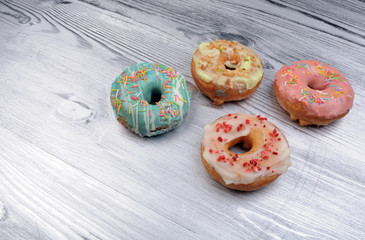 Fresh tasty donuts in soft colorful glaze on a silver wooden background