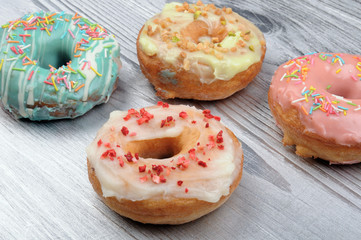 Naklejka na ściany i meble Fresh tasty donuts in soft colorful glaze on a silver wooden background