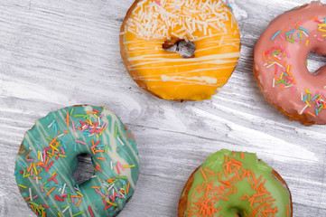 Fresh tasty donuts in soft colorful glaze on a silver wooden background