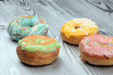 Fresh tasty donuts in soft colorful glaze on a silver wooden background