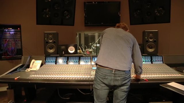 An audio engineer behind the soundboard in a music studio.