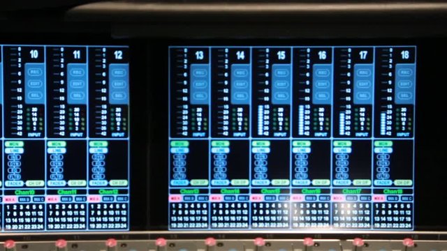 Close up pan of Volume Unit (VU) meters on an audio console in a music studio.