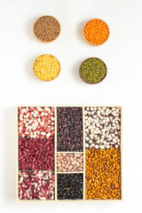 Four bowls with lentils and beans with a wooden box. Top view