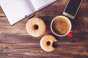 Donuts and coffee lying on rustic wooden background with open no
