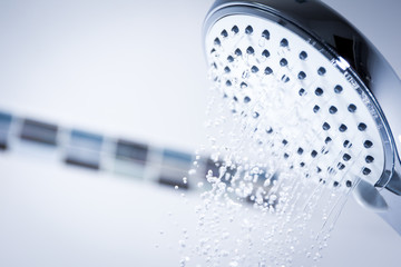 Naklejka na ściany i meble Image of a modern shower head splashing water close up background.