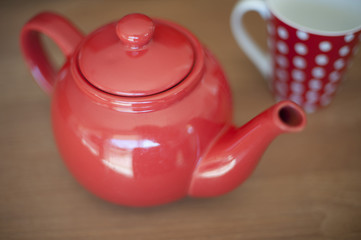 Glossy Red Teapot on Wooden Table with a Mug