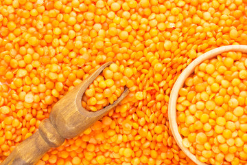 Yellow lentils, scoop and wooden bowl