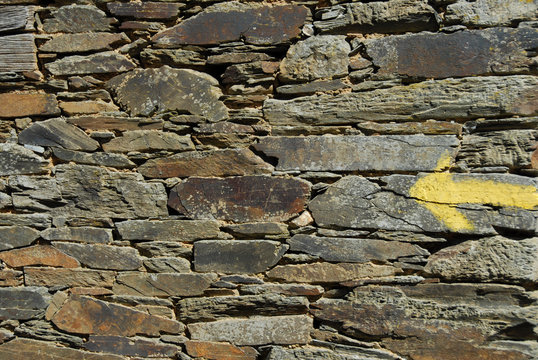 Gelber Pfeil auf Steinmauer am Jakobsweg in Spanien
