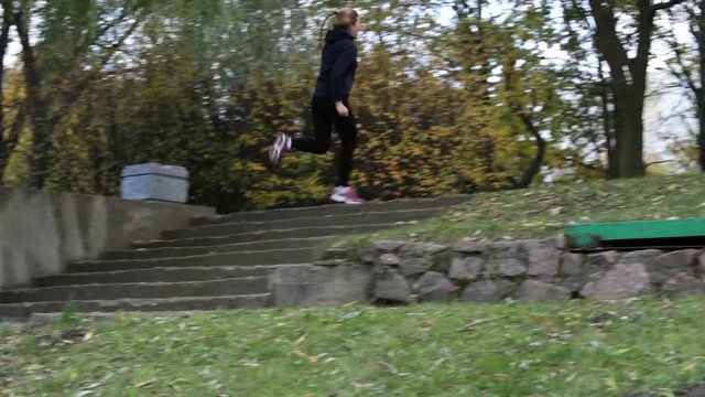 Young woman running up the stairs and going on the scamper in the autumn park