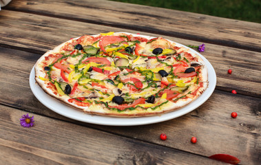 Vegetable pizza served on white plate on wooden table 


