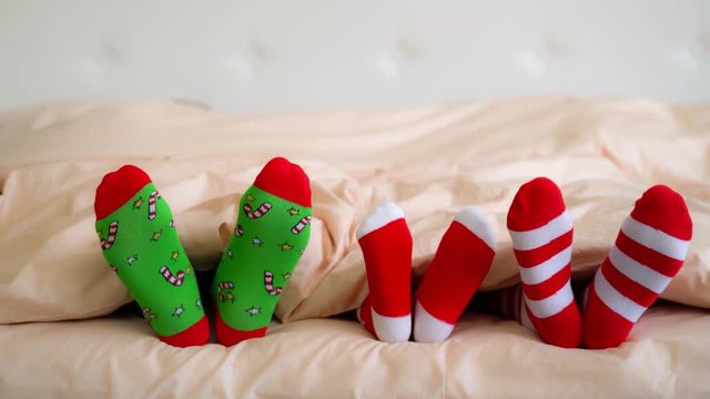 Family in Christmas socks in bed. Mother; father and baby having fun together. People relaxing at home. Winter holiday Xmas and New Year concept